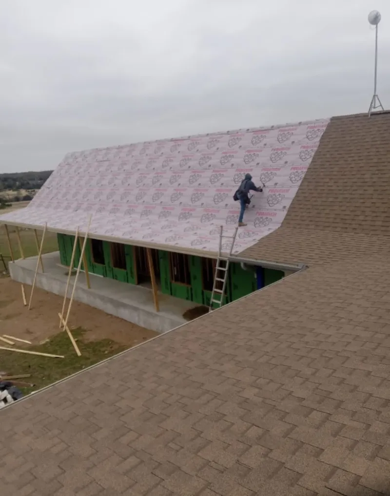 Worker preparing underlayment for a metal roof installation in Penitas